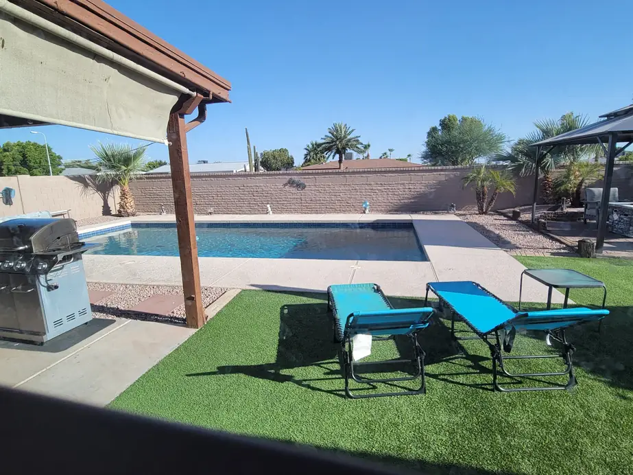 Rental home pool in daylight with turf, loungers and a pergola edge in Phoenix
